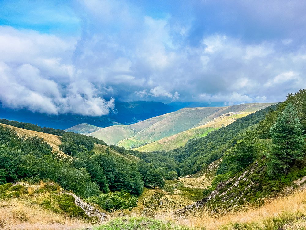 Sweeping view across the Pyrenees from the Camino Francés between Borda and Roncesvalles, with low clouds drifting across the mountains.