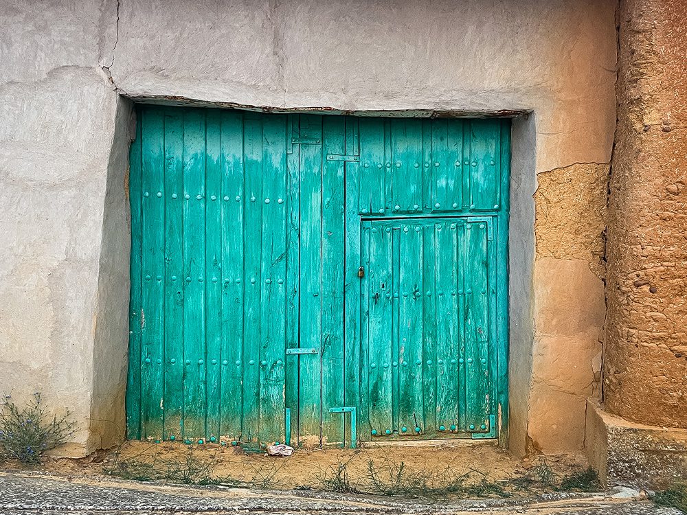 Weathered turquoise wooden doors in a village on the Camino Francés towards Sahagún