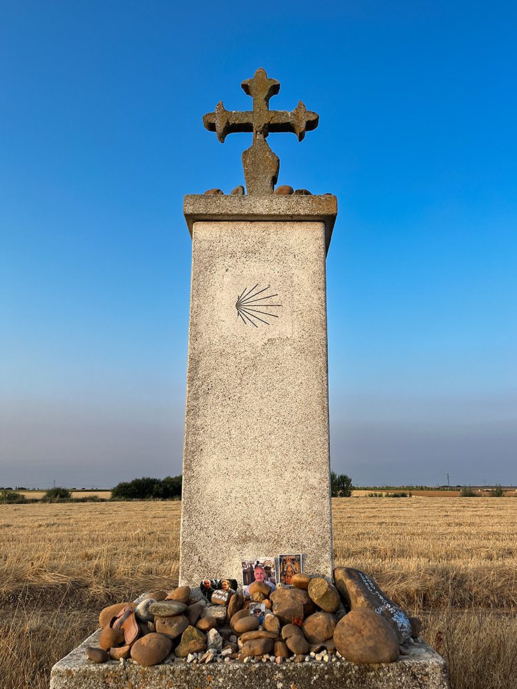 Camino memorial with pilgrim scallop shell beside the route to Mansilla de las Mulas