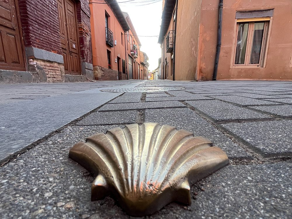 Camino scallop shell waymarker set into a street in Mansilla de las Mulas