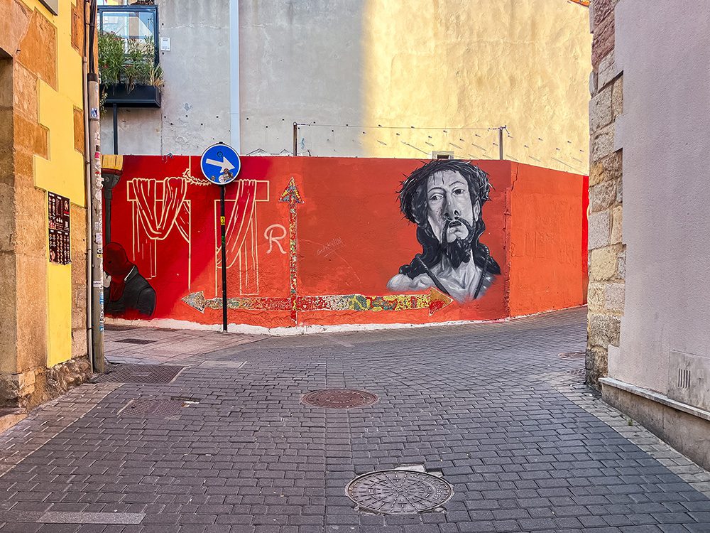 Street art depicting Christ on a red wall in León