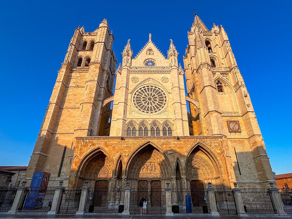 Gothic west façade and rose window of León Cathedral in evening sunlight