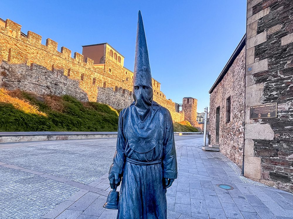 Nazarene Lambrión Chupacandiles statue with the Templar Castle behind in Ponferrada