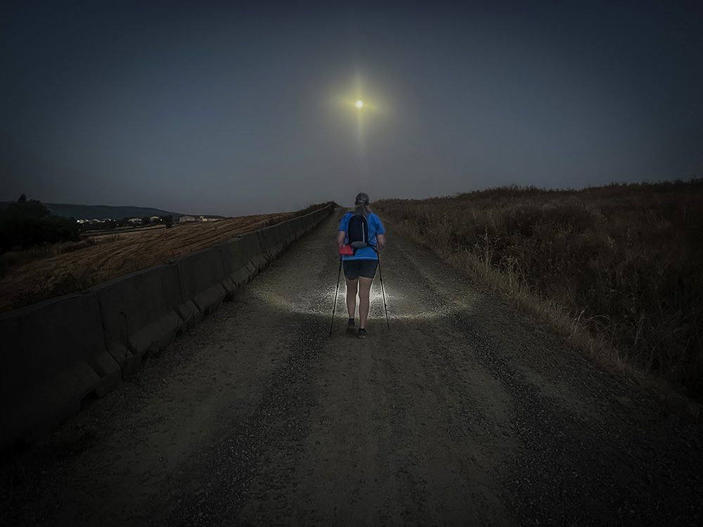 Pilgrim walking by head torch before dawn on the Camino Francés from Redecilla del Camino