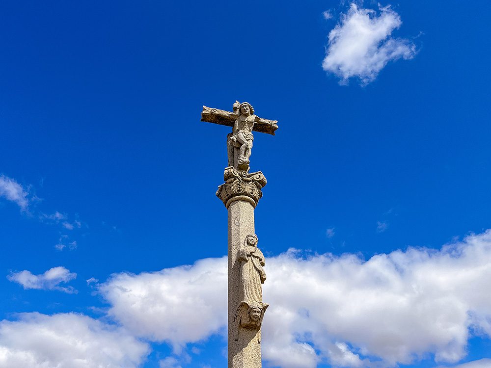 Stone crucifix beneath a deep blue sky on the Camino Francés towards El Burgo Ranero