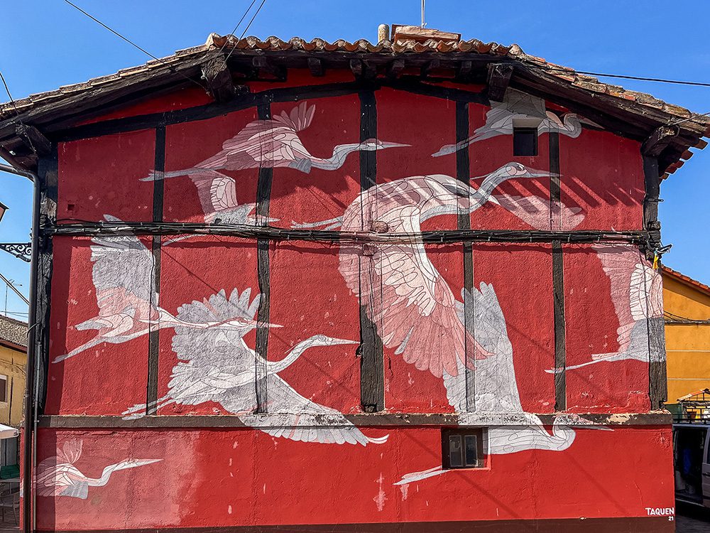 White crane mural on a traditional red building in Agés on the Camino Francés